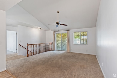 Unfurnished room featuring ceiling fan, vaulted ceiling, and light colored carpet