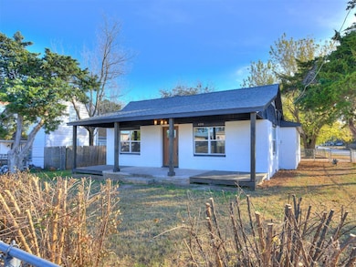 View of front of property featuring a porch, brick siding, and a shingled roof