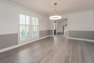 Empty room featuring ornamental molding, stairway, wood finished floors, and baseboards