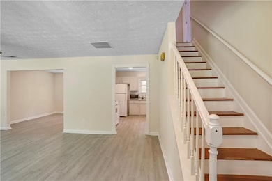 Stairway with wood finished floors, a textured cei