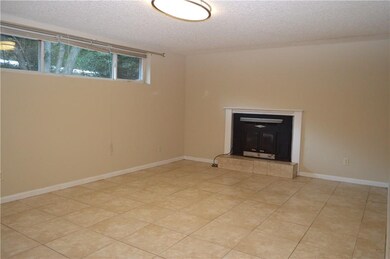 Den with wood burning fireplace and tile floors.