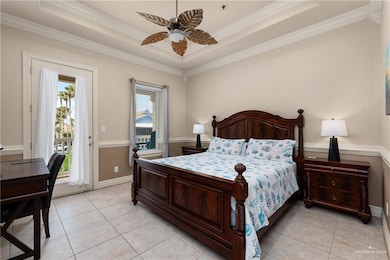 Bedroom with access to exterior, light tile patterned floors, ornamental molding, a raised ceiling, and a ceiling fan