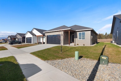 View of front facade with a front lawn, driveway, a garage, and a shingled roof
