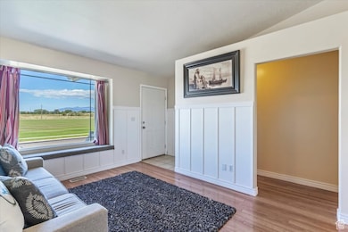 Living area featuring light wood finished floors, wainscoting, and a decorative wall
