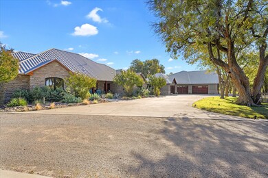 View of front of home with driveway, stone siding, a metal roof, and a standing seam roof