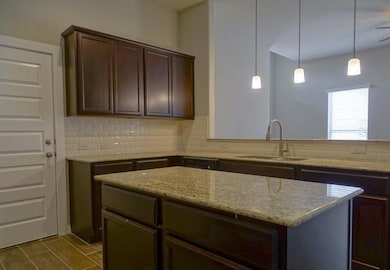 Kitchen featuring tasteful backsplash, light ston