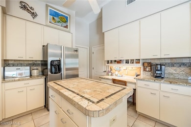 Kitchen featuring ceiling fan, white cabinets, lig