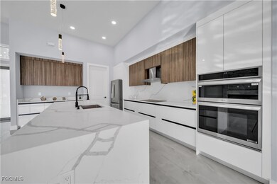 Kitchen with brown cabinets, light stone countertops, modern cabinets, hanging light fixtures, and recessed lighting