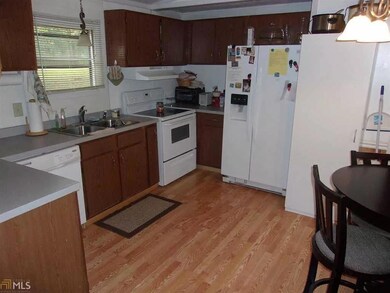 Kitchen with white appliances, light wood-type flooring, light countertops, and under cabinet range hood