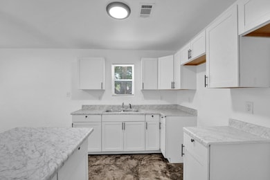 Kitchen featuring a sink, light countertops, and white cabinetry