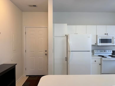 Front door on the left. Kitchen features white appliances, white cabinets, tile patterned floors, light countertops, and electric panel
