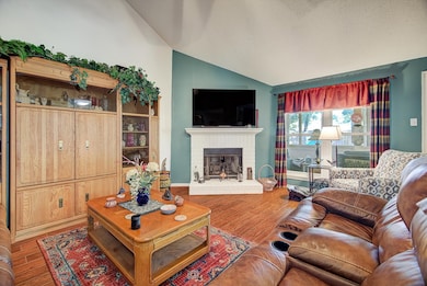 Living Room – Spacious living area featuring vaulted ceilings, a ceiling fan, and wood-look flooring, offering a comfortable setting for everyday living.