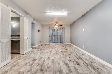Empty room with light wood finished floors, a ceiling fan, and a textured ceiling