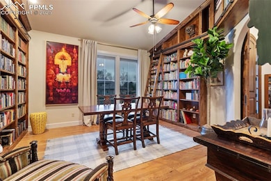 Dining room featuring arched walkways, baseboards, light wood-style floors, and a ceiling fan