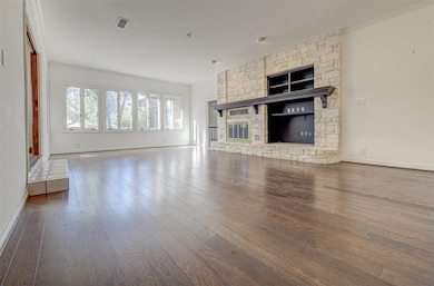 Unfurnished living room featuring a fireplace, wood-type flooring, and ornamental molding
