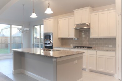 Kitchen with backsplash, pendant lighting, light tile patterned floors, light stone counters, and white cabinetry