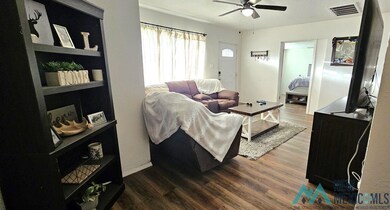 Living area featuring dark wood-type flooring and a ceiling fan