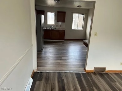 Kitchen featuring dark wood-style flooring, freestanding refrigerator, light countertops, and tasteful backsplash