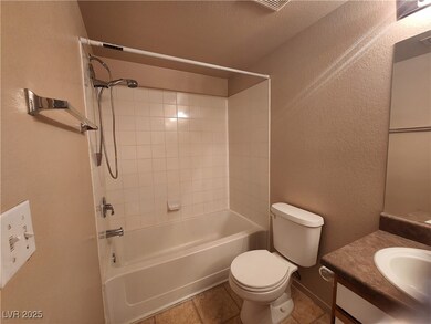 Bathroom featuring a textured wall, vanity, shower / bathtub combination, and light tile patterned floors