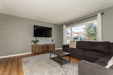 Living area featuring wooden walls, a textured ceiling, and wood finished floors