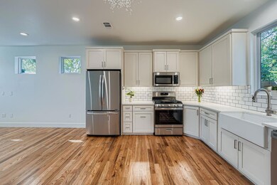 Kitchen featuring healthy amount of natural light, stainless steel appliances, decorative backsplash, white cabinets, and recessed lighting