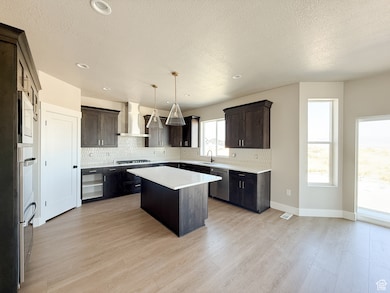 Kitchen with decorative backsplash, a center island, dark brown cabinets, pendant lighting, and a textured ceiling
