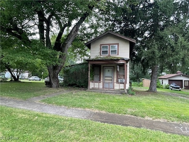 View of front of property featuring a front yard, a porch, and an outdoor structure