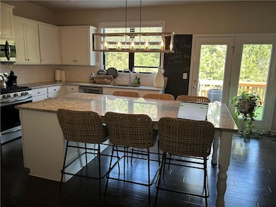 Kitchen with a kitchen island, stainless steel appliances, light stone countertops, backsplash, and a breakfast bar area