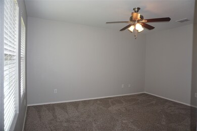 Carpeted empty room featuring a ceiling fan and baseboards