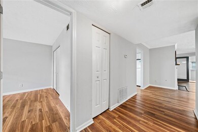 Hall with wood finished floors, baseboards, and a textured ceiling
