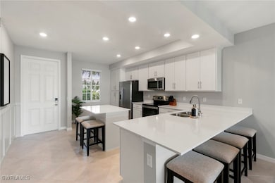 Kitchen featuring a breakfast bar, a center island, recessed lighting, white cabinetry, and stainless steel appliances