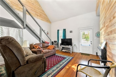 Living area featuring high vaulted ceiling, stairway, and hardwood / wood-style floors