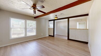 Unfurnished room featuring beamed ceiling, a ceiling fan, light wood-type flooring, and a textured ceiling