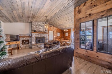 Living area featuring hardwood / wood-style flooring, lofted ceiling, wood walls, a fireplace, and ceiling fan
