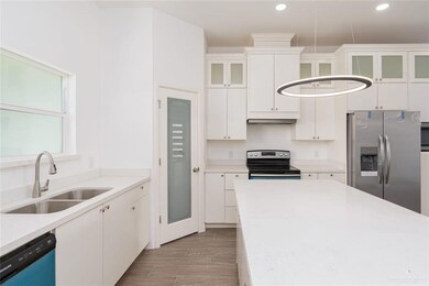 Kitchen with glass insert cabinets, light countertops, white cabinets, stainless steel appliances, and a sink