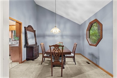 Carpeted dining area with high vaulted ceiling and a chandelier