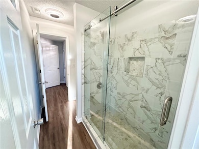Bathroom with wood-type flooring, a shower with sh