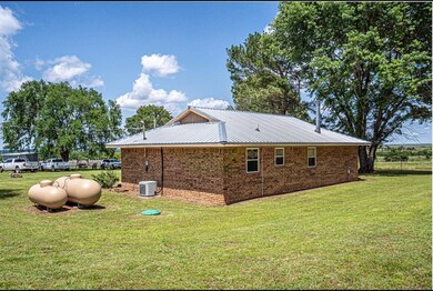 View of side of property featuring a yard, brick siding, and metal roof