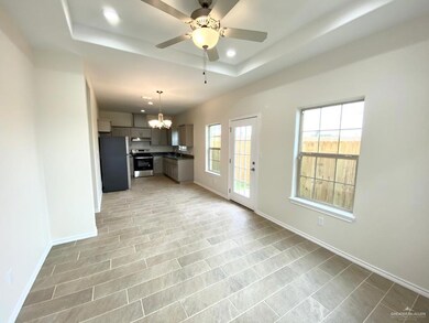 Unfurnished living room featuring a raised ceiling, recessed lighting, a chandelier, and ceiling fan