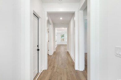 Hallway with light wood-type flooring and recessed lighting