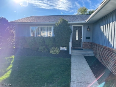 Entrance to property featuring a lawn, roof with shingles, and board and batten siding