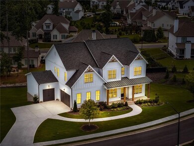 Modern farmhouse with board and batten siding, a shingled roof, covered porch, driveway, and a front yard