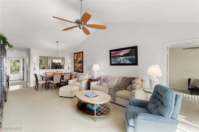 Carpeted living room featuring ceiling fan, high vaulted ceiling, and a chandelier