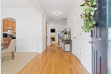 Entrance foyer featuring stairs, light wood-style floors, and arched walkways