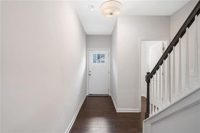 Doorway with dark wood finished floors, baseboards, and stairs