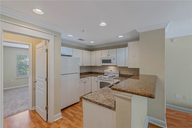 Kitchen with white cabinetry, crown molding, white