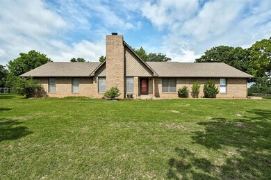 View of front of property featuring a chimney, a front yard, and brick siding