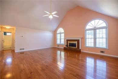 Unfurnished living room with high vaulted ceiling, light wood-type flooring, a fireplace, and a ceiling fan