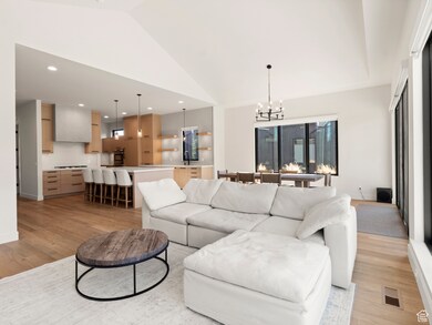 Living area with a chandelier, light wood-type flooring, high vaulted ceiling, and recessed lighting