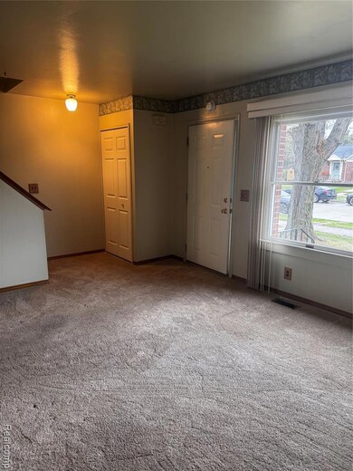 Unfurnished living room featuring carpet and baseboards